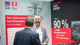 Zwei Männer unterhalten sich freudig vor einem Ausstellungsstand beim Treffpunkt Netze 2025